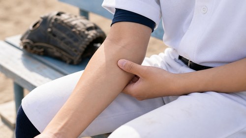 野球肘の症状として肘の内側を確認する様子