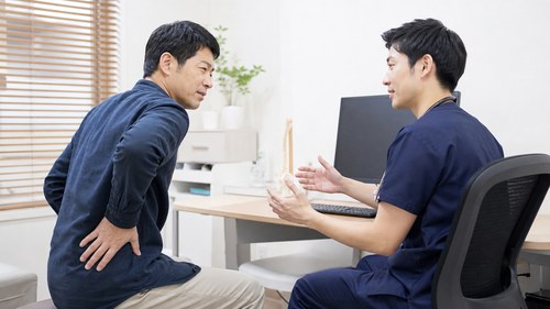 ぎっくり腰で医療機関への相談をする男性