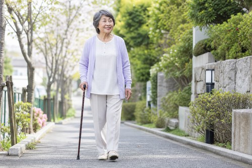 股関節の痛みが強いときに杖を使って歩く女性