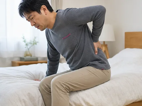 ベッドから落ち着いて起き上がる男性