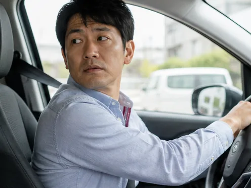 運転中の後方確認で首を動かす男性