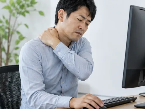 パソコン作業中に首肩の負担を感じる男性