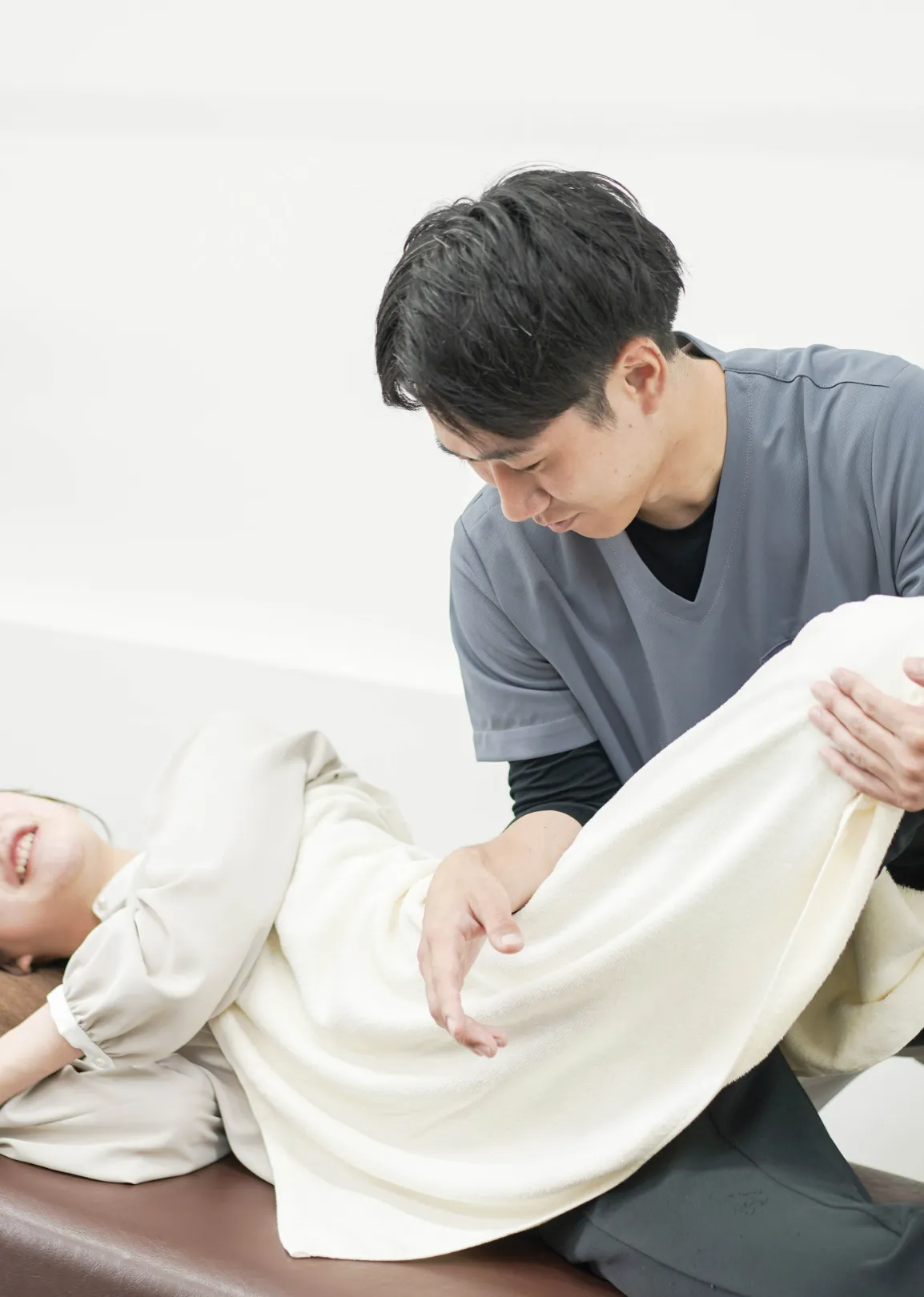 横向きの姿勢で肩と腕の可動域を調整する整体施術の様子