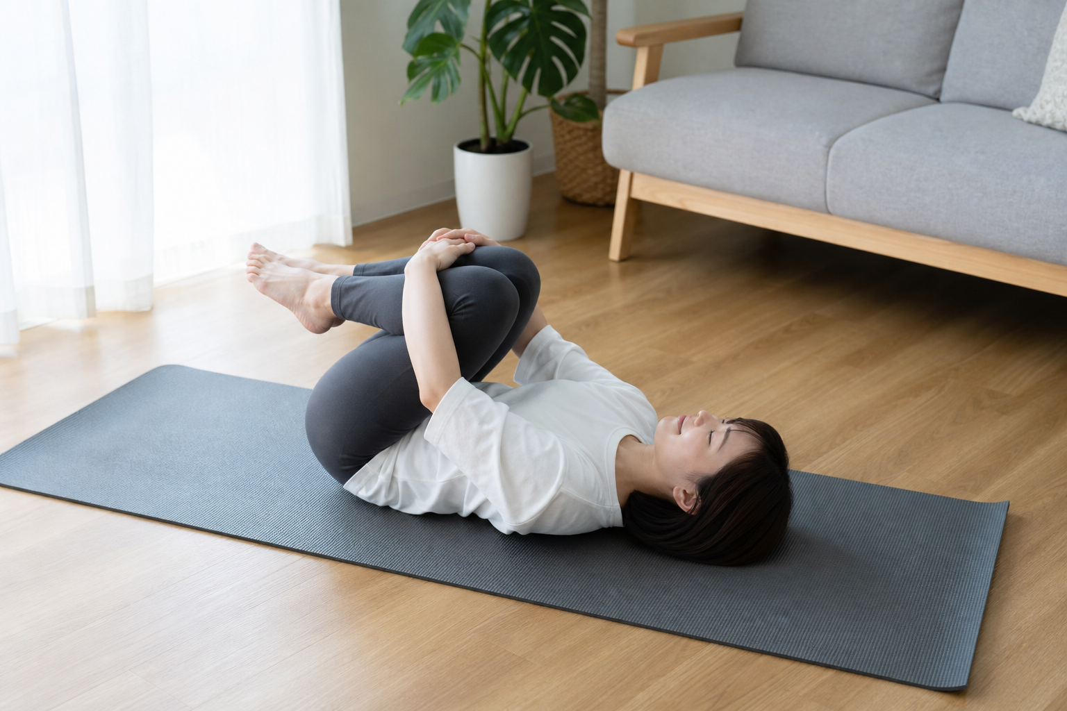 仰向けで膝を抱えて腰を伸ばす日本人女性のイメージ