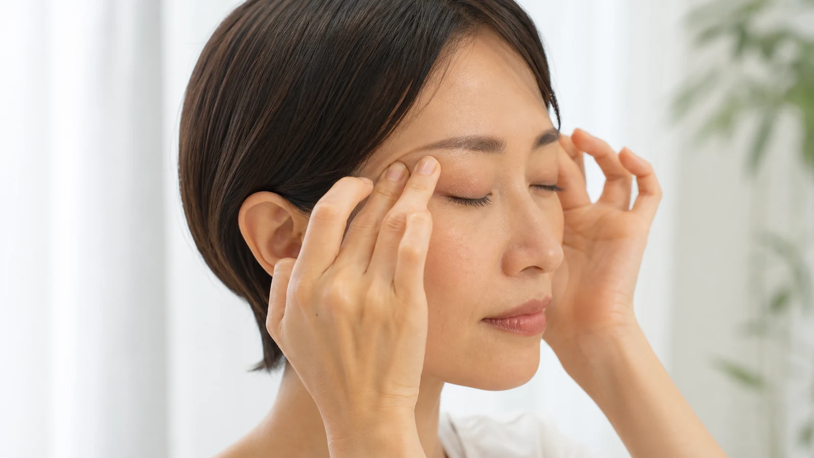 眼球を押さずこめかみに優しく触れる様子