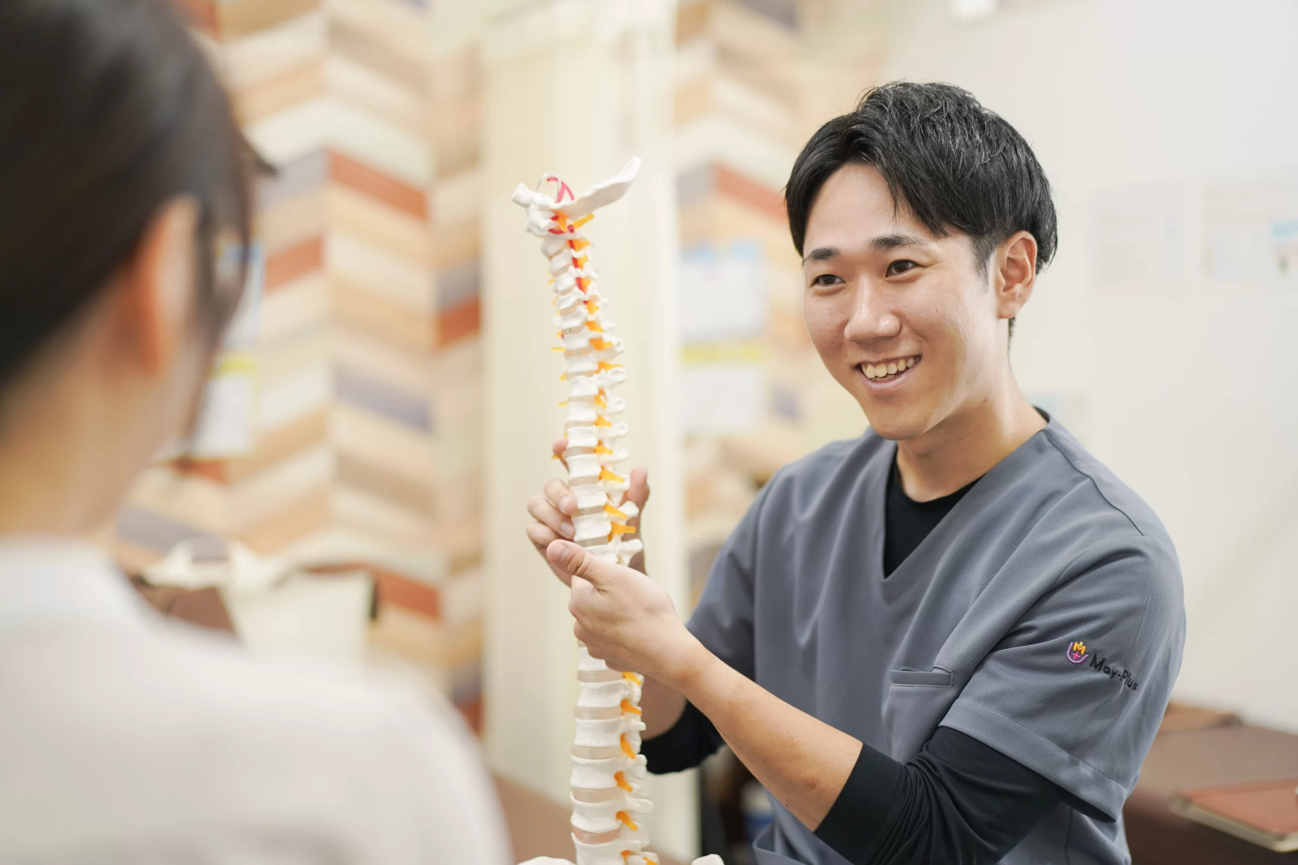 CUREPROで骨格模型を使って体の状態を説明する施術者