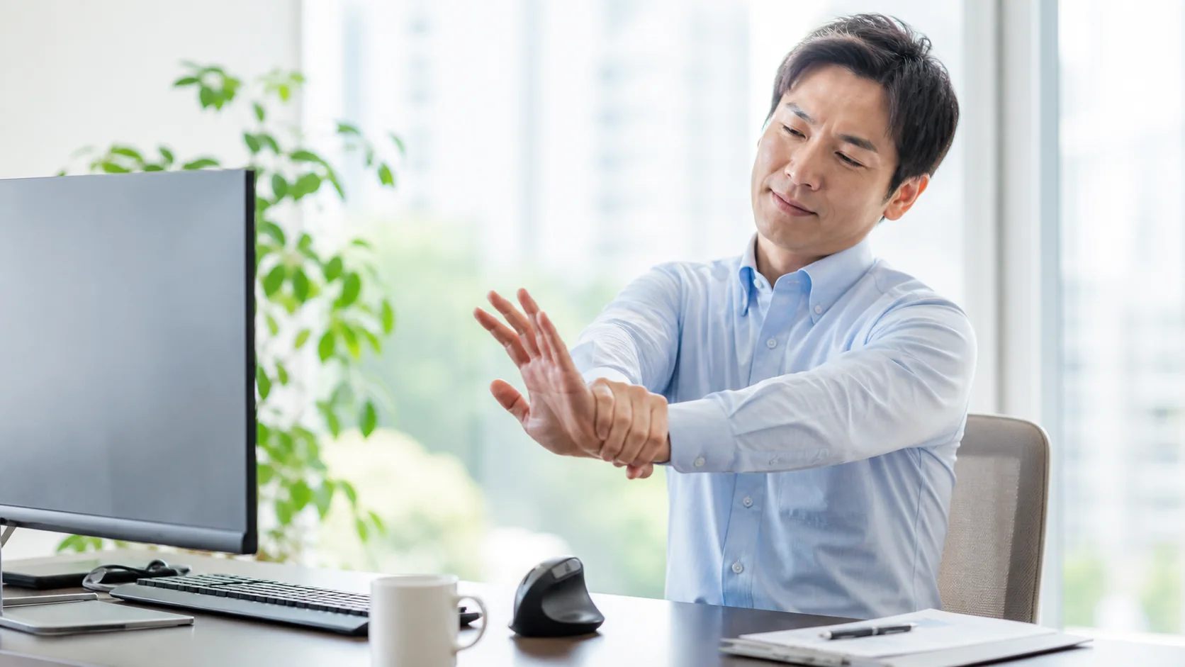 手首を休ませて作業環境を整える会社員