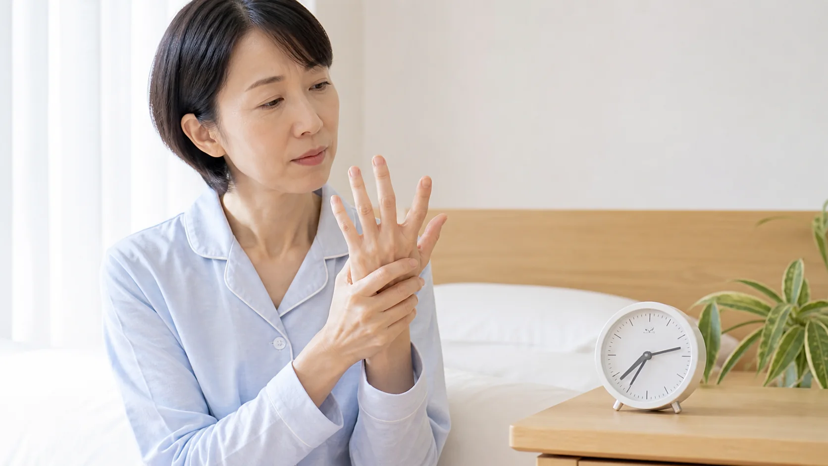 朝の手のこわばりが続く時間を確認する女性