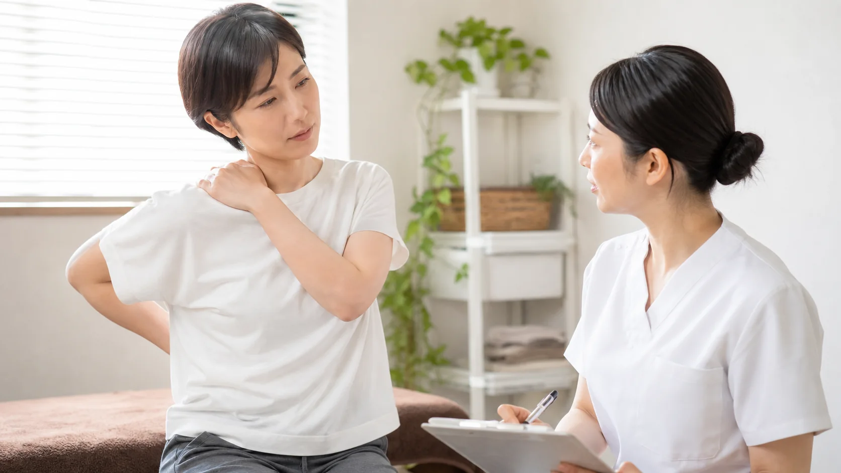 肩の動かしにくさを施術者に相談する女性