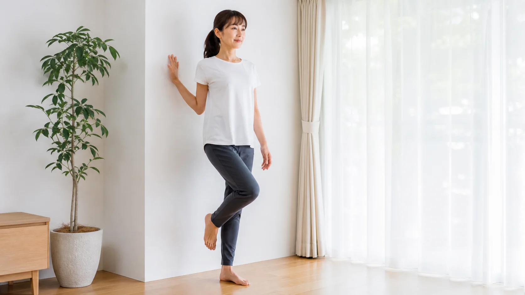 壁に手を添えて片足立ちを練習する女性