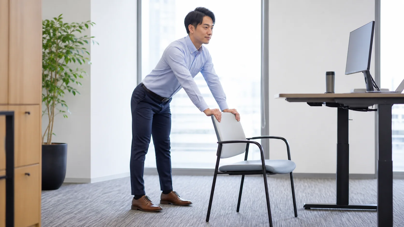 椅子を支えに腰と股関節をゆるめる男性