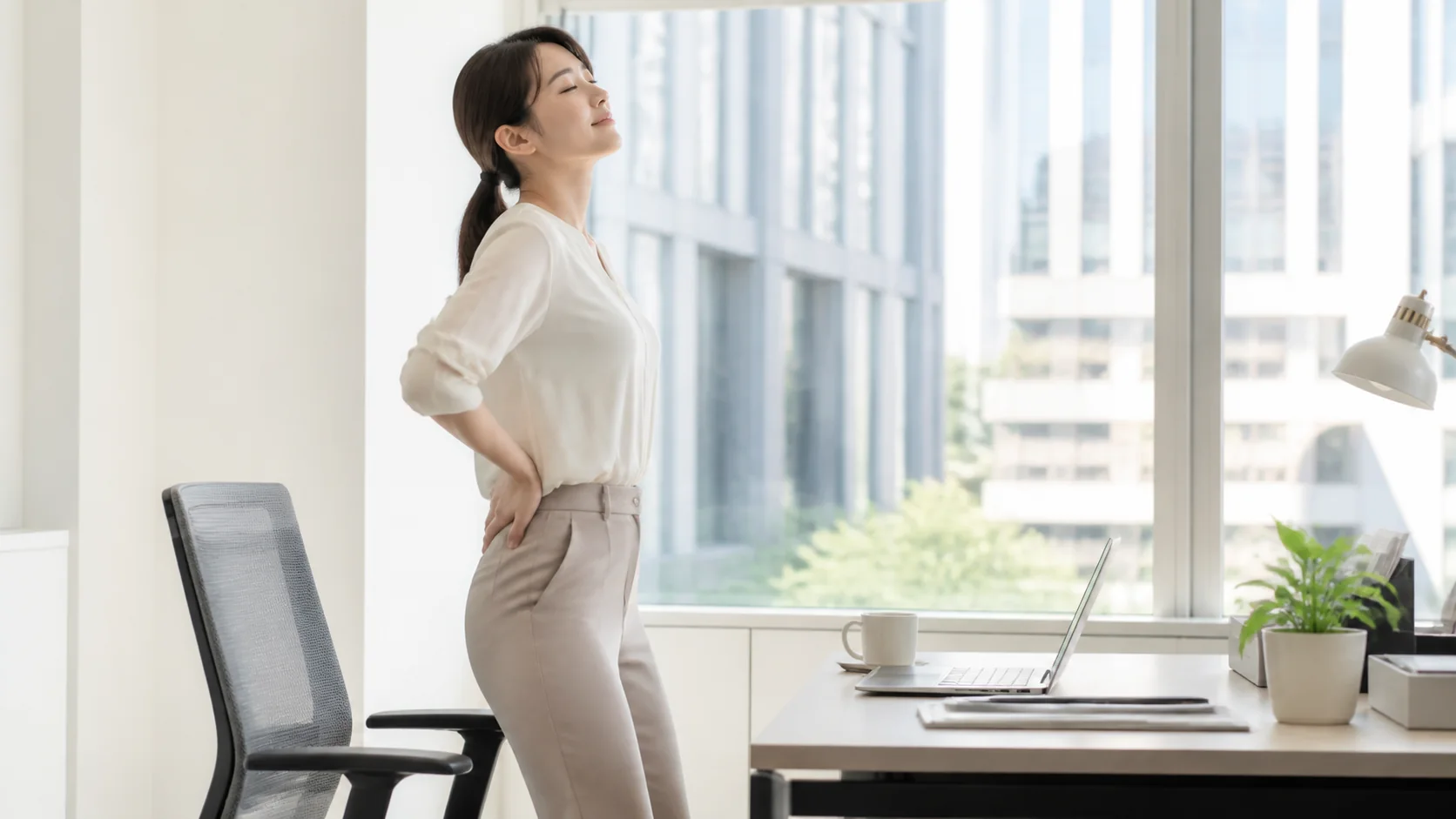 椅子から立って腰を伸ばす女性