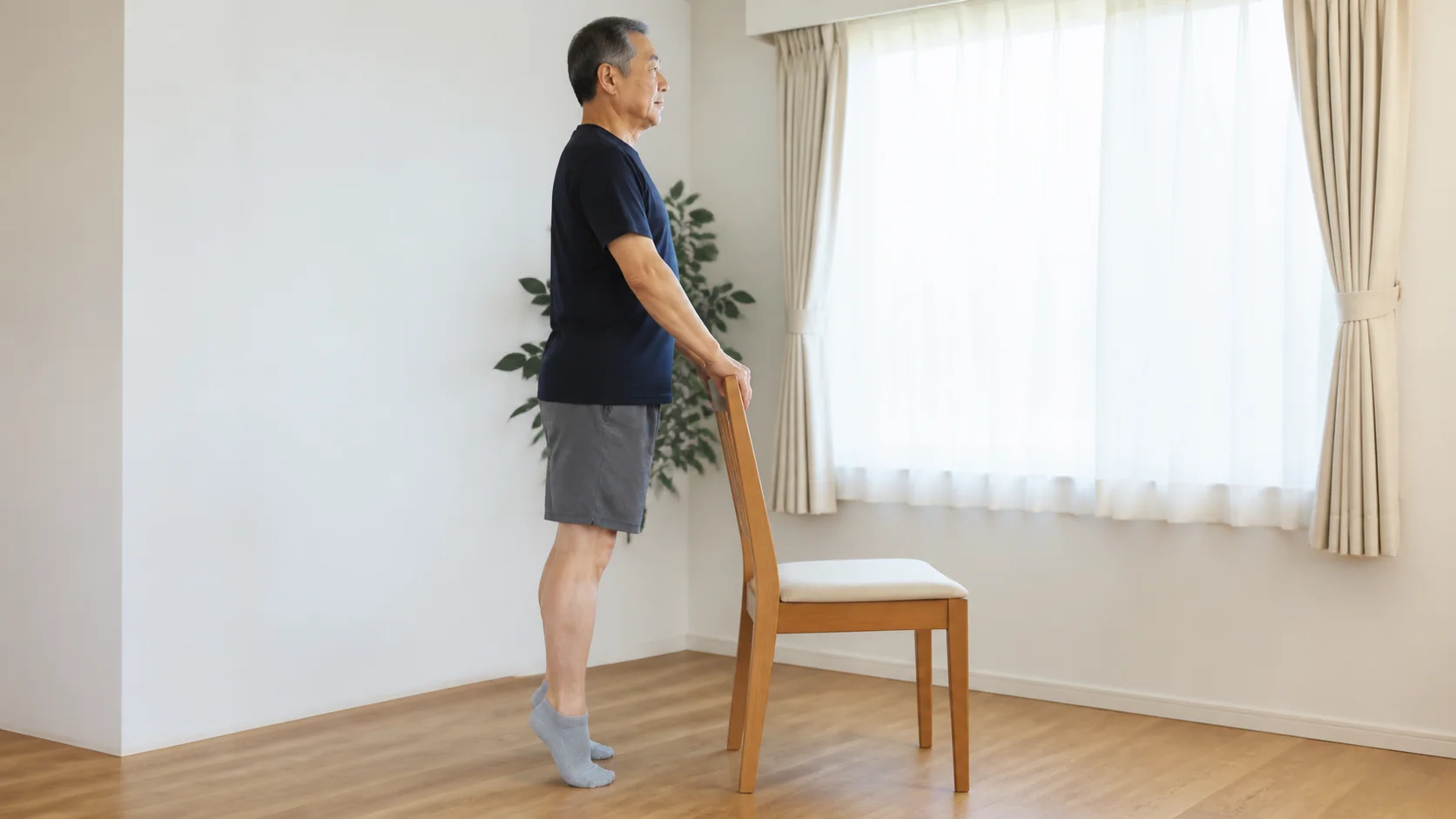 椅子につかまってかかと上げを行う高齢男性
