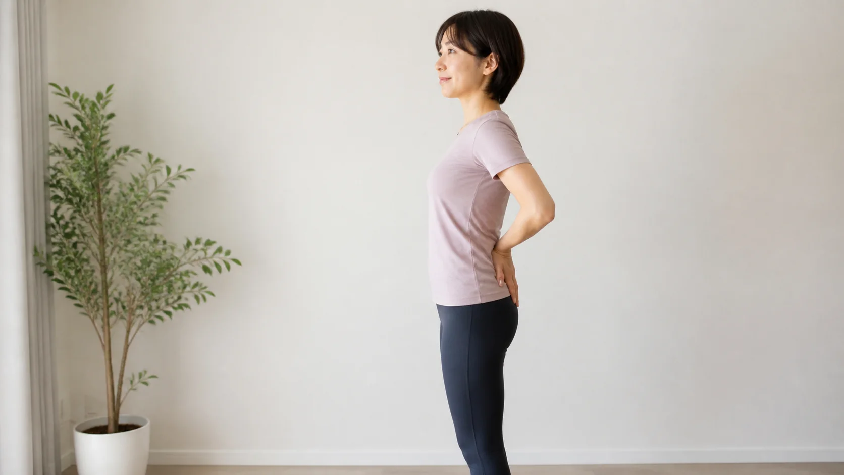 壁を使って反り腰をセルフチェックする女性