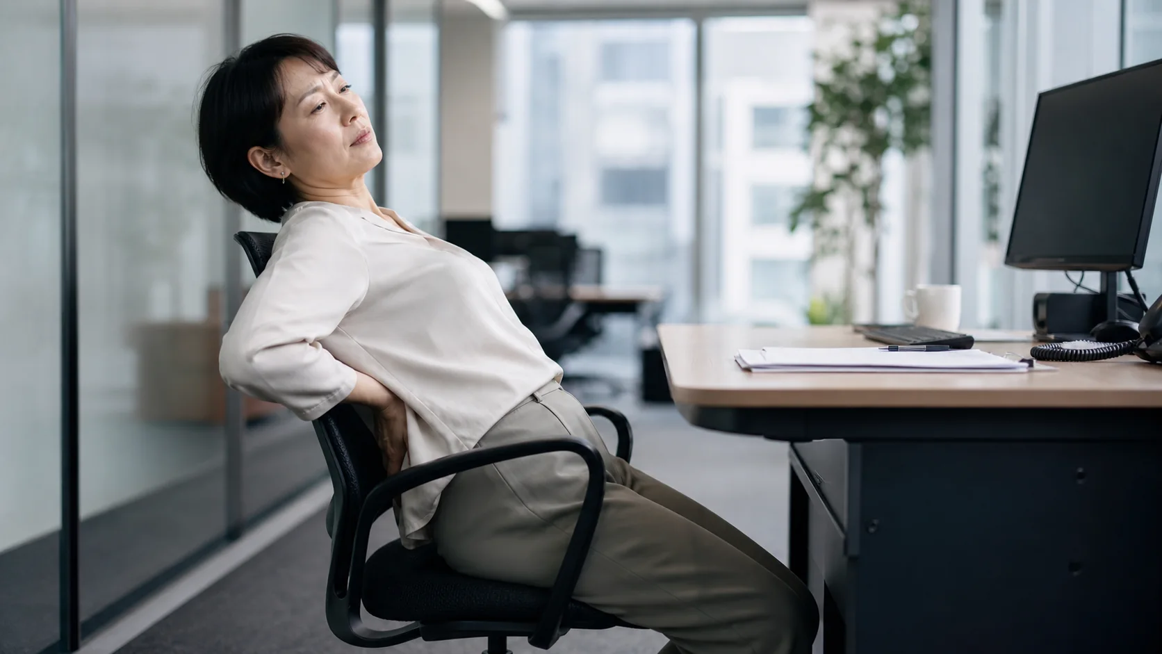 長時間座った後に尾てい骨周辺を気にする女性
