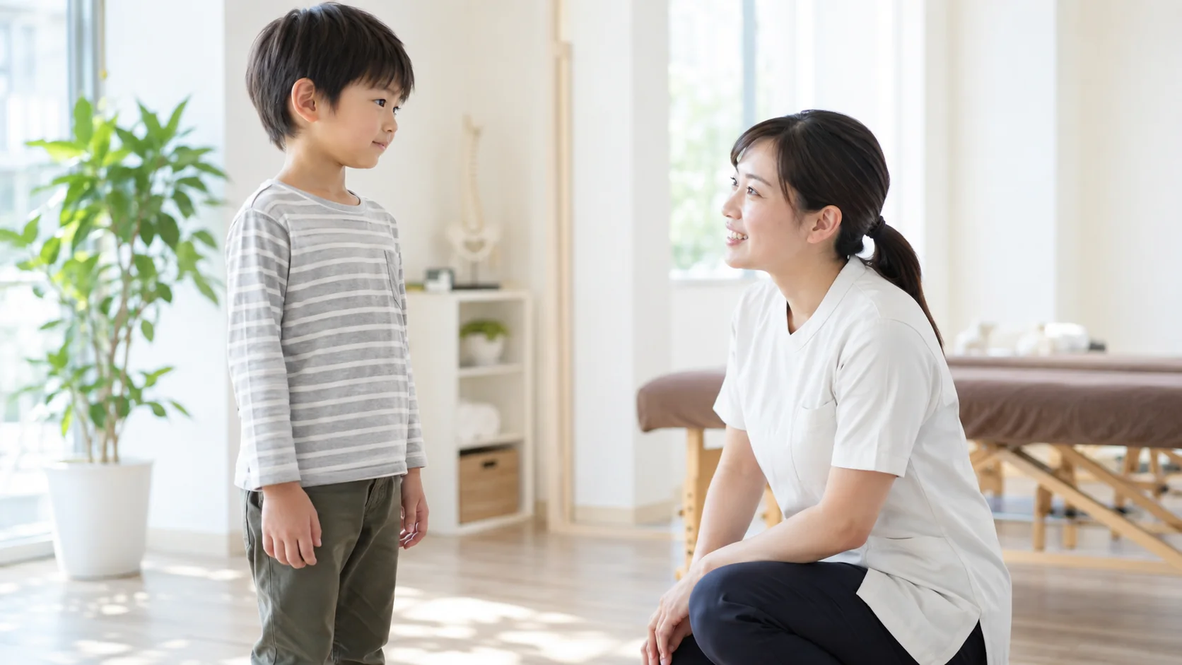 子どもに声をかけながら立ち姿勢を確認する整体院の担当者
