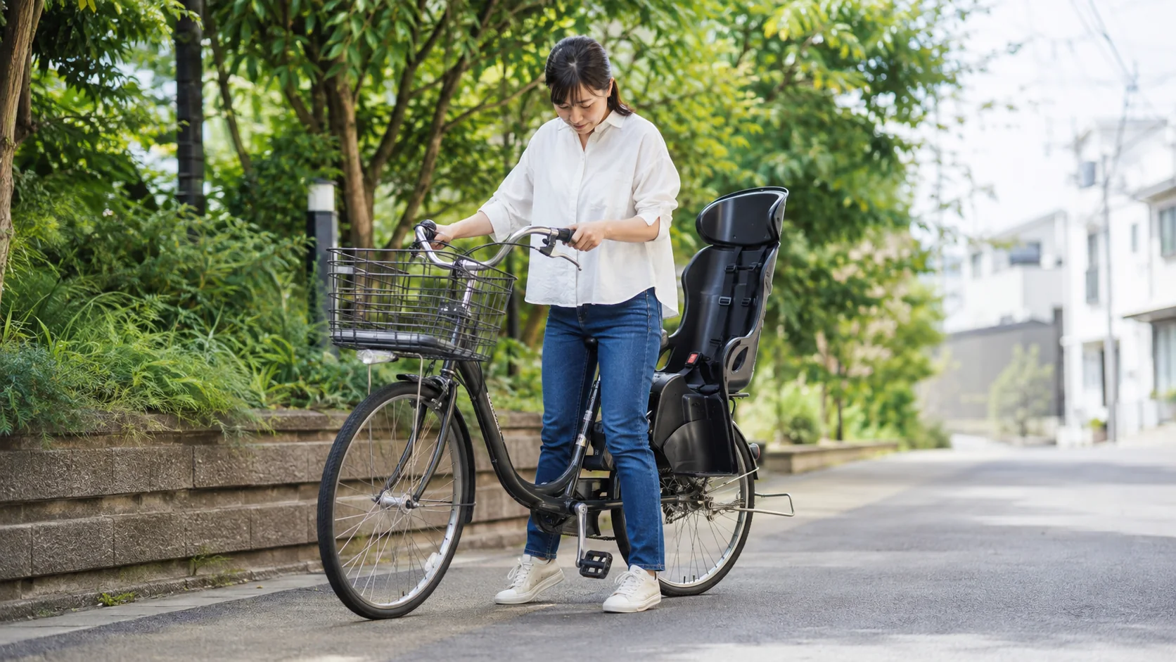子乗せ自転車で安全な足つきを確認する女性