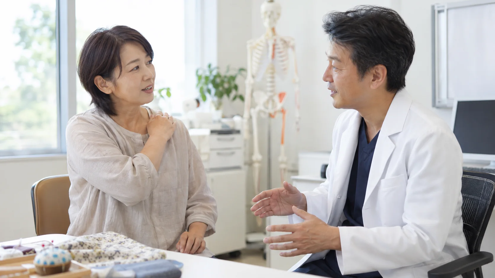 肩の不調を医師に相談する縫い物をする女性